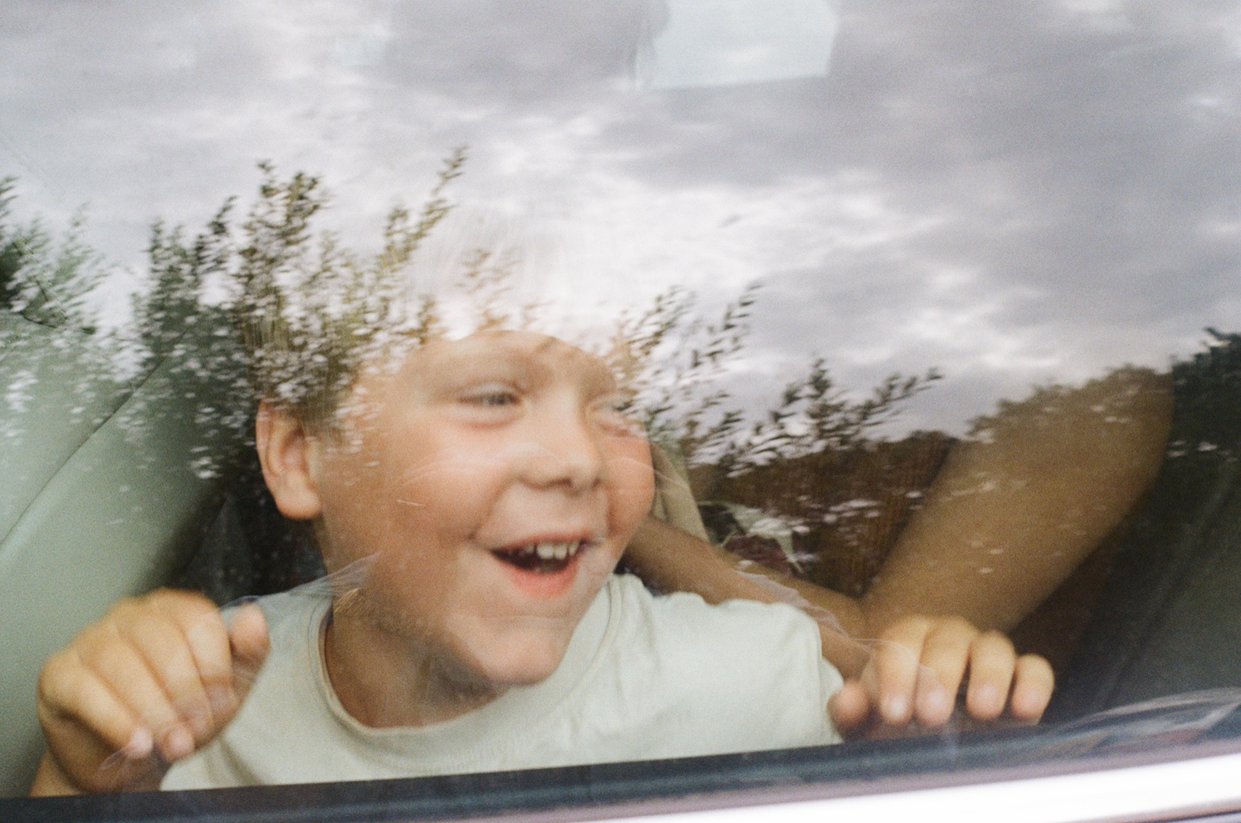 I got very lucky with this one. Pure joy captured in 1/15th of a second. I feel the reflection of the trees in the window only improves the image, and draws all the attention to the expression.